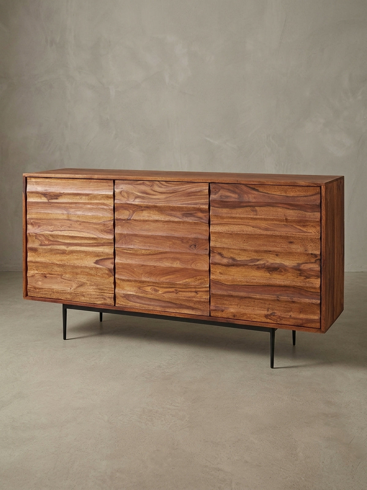 Frontansicht des 150 cm breiten Sheesham Massivholz Sideboards. Die drei grifflosen Türen der Kommode bestechen durch ihr wellenartiges Design und die natürliche braune Maserung.