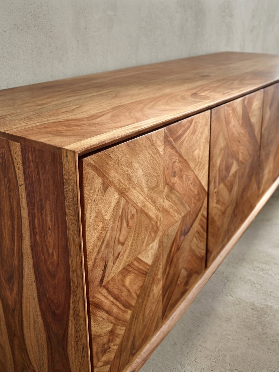 Fokussierte Aufnahme einer der drei grifflosen Türen, die das präzise gefertigte geometrische Holzparkett-Muster des modernen Sideboards betont._