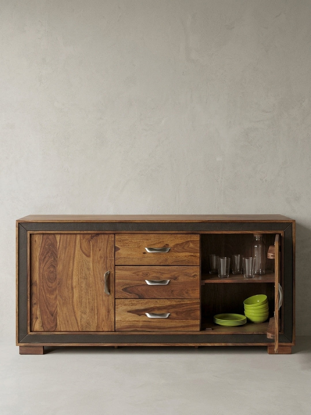 Freigestelltes Design Sideboard aus massivem Sheeshamholz in der Frontansicht. Die 160cm breite Kommode zeigt drei mittige Schubladen, zwei Holztüren und geschwungene Silbergriffe._