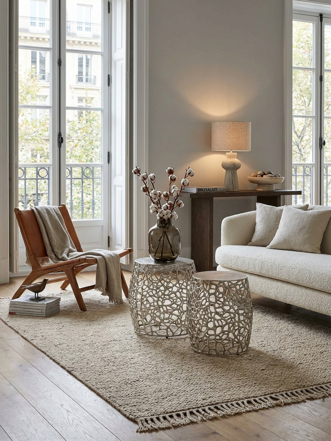 Zwei silberne Design-Beistelltische aus Aluminium im Set, platziert neben einem Sofa in einem modern-organisch eingerichteten Wohnzimmer mit Holzboden._