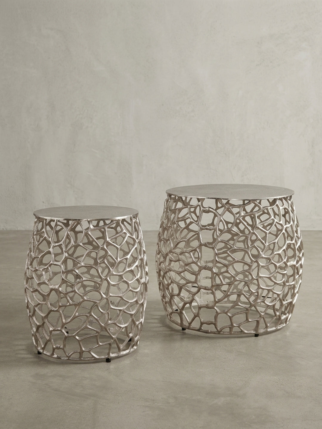 Silberner Satztisch aus Metall in 3/4-Ansicht, die die bauchige Form und das komplexe, durchbrochene Design des runden Wohnzimmertisches hervorhebt._