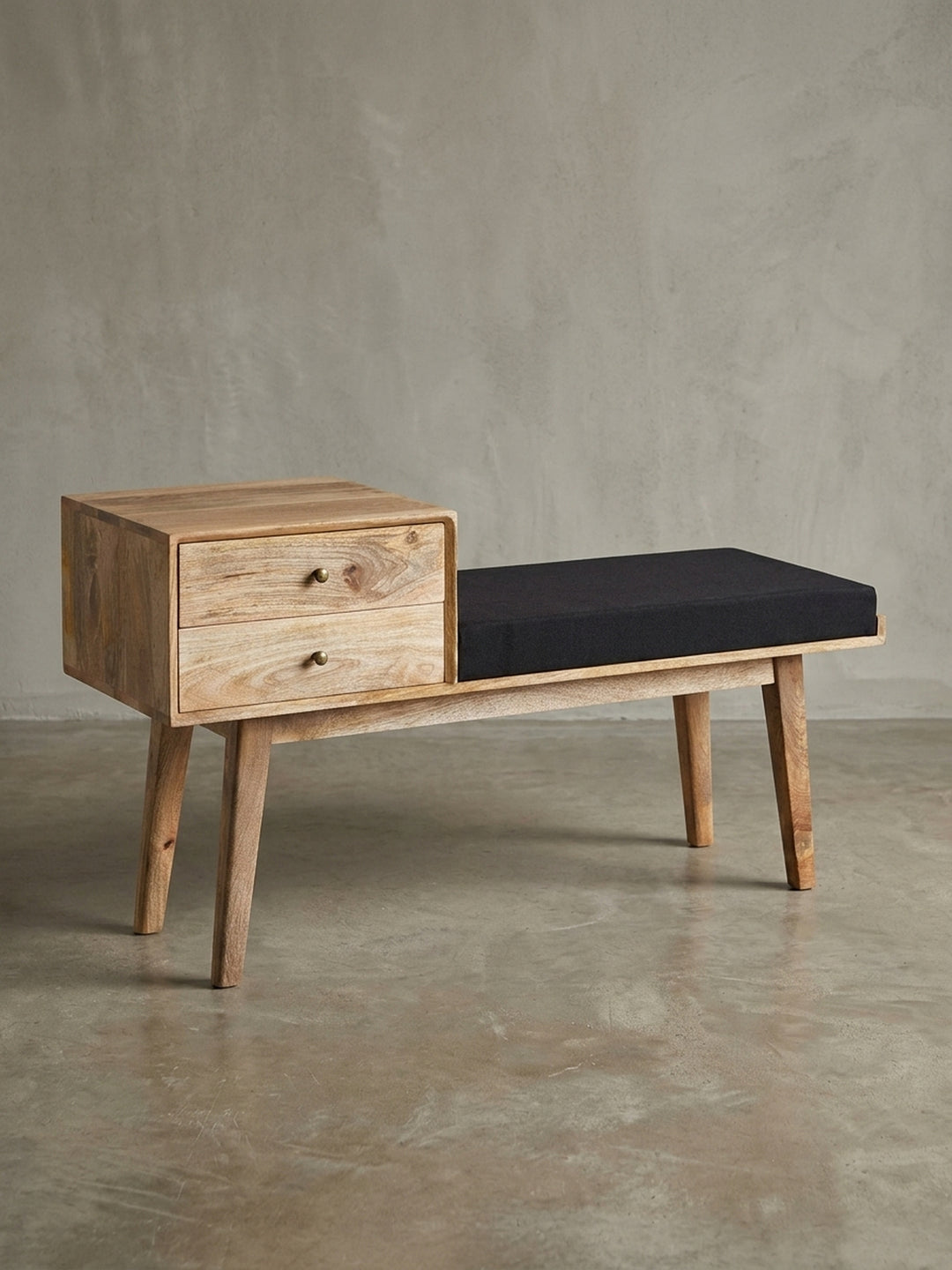 Freigestellte Frontansicht der Sitzbank im Retro-Stil aus Mangoholz mit zwei Schubladen und schwarzem Sitzpolster, Maße 120x65x40 cm._