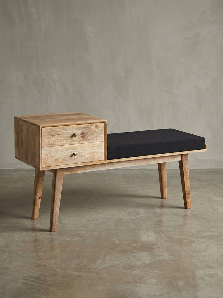 Freigestellte Frontansicht der Sitzbank im Retro-Stil aus Mangoholz mit zwei Schubladen und schwarzem Sitzpolster, Maße 120x65x40 cm._