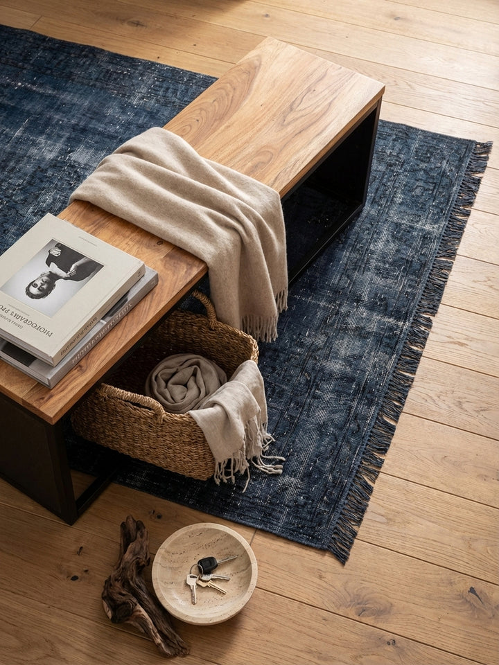 Sitzbank aus Holz und Metall von oben betrachtet, positioniert auf einem Vintage-Teppich im Flur, zeigt die schlanke und funktionale Silhouette des Möbelstücks._