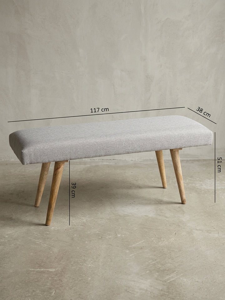 Rückwärtige Detailansicht der grauen Bettbank im Retro-Design. Die saubere Verarbeitung des Baumwollbezugs und die stabile Befestigung der ausgestellten Mangoholzbeine garantieren_