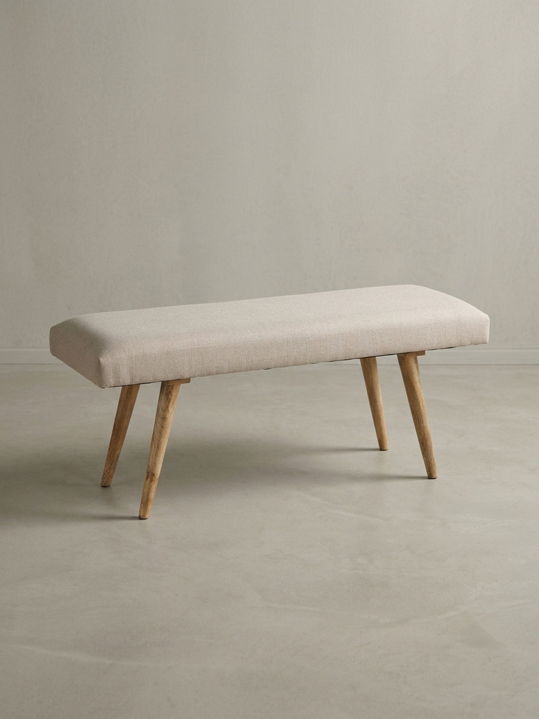 Alternative Perspektive der Esszimmerbank in Beige. Der helle Baumwollstoff spannt sich faltenfrei über das Polster, während die 39 cm Bodenfreiheit optische Leichtigkeit schafft._