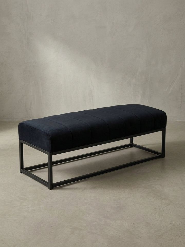 Elegante Polsterbank in Schwarz mit gestepptem Samt und filigranem Eisengestell, die Tiefe und Form aus einer seitlichen Perspektive zeigt._