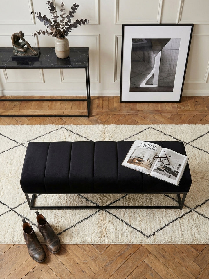 Blick von oben auf eine moderne schwarze Samtbank auf einem Beni Ourain Teppich, perfekt arrangiert in einem eleganten Flur mit minimalistischer Konsole._