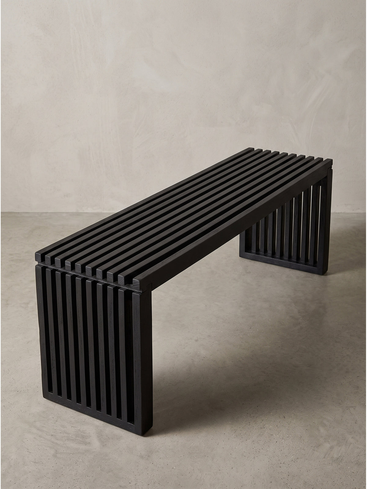 Angewinkelte Ansicht der schwarzen Holz-Sitzbank mit sichtbarer blockhafter Silhouette und präzisem Latten-Design.
