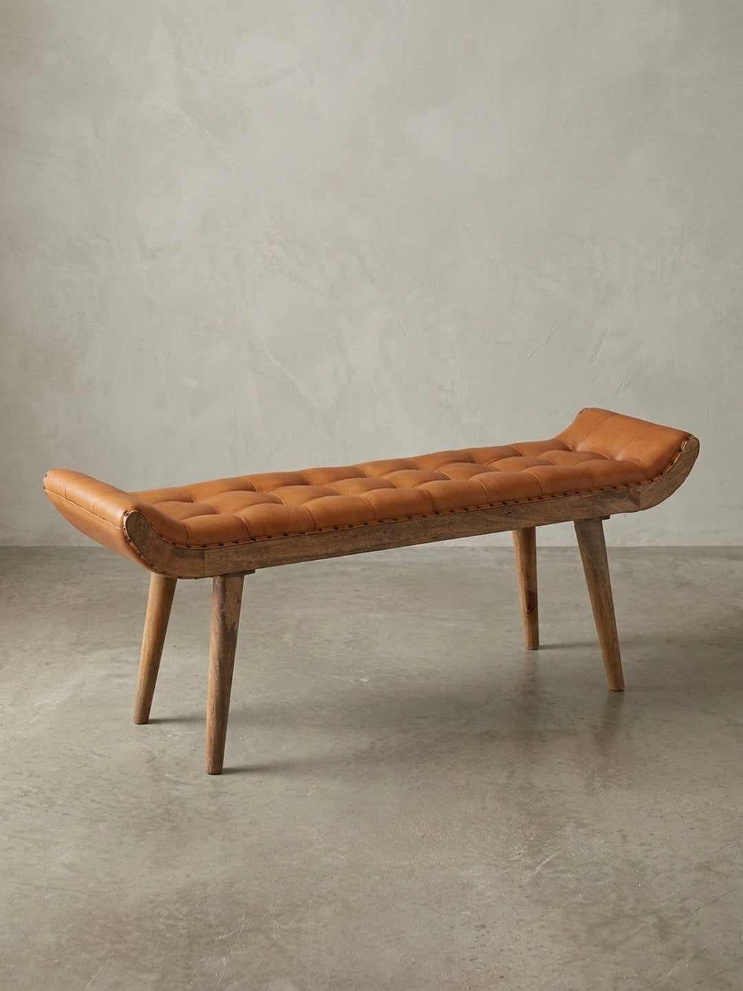 Die Design Sitzbank aus massivem Mangoholz und braunem Echtleder in der Gesamtübersicht. Die getuftete Oberfläche im Chesterfield-Stil ist das zentrale Merkmal._