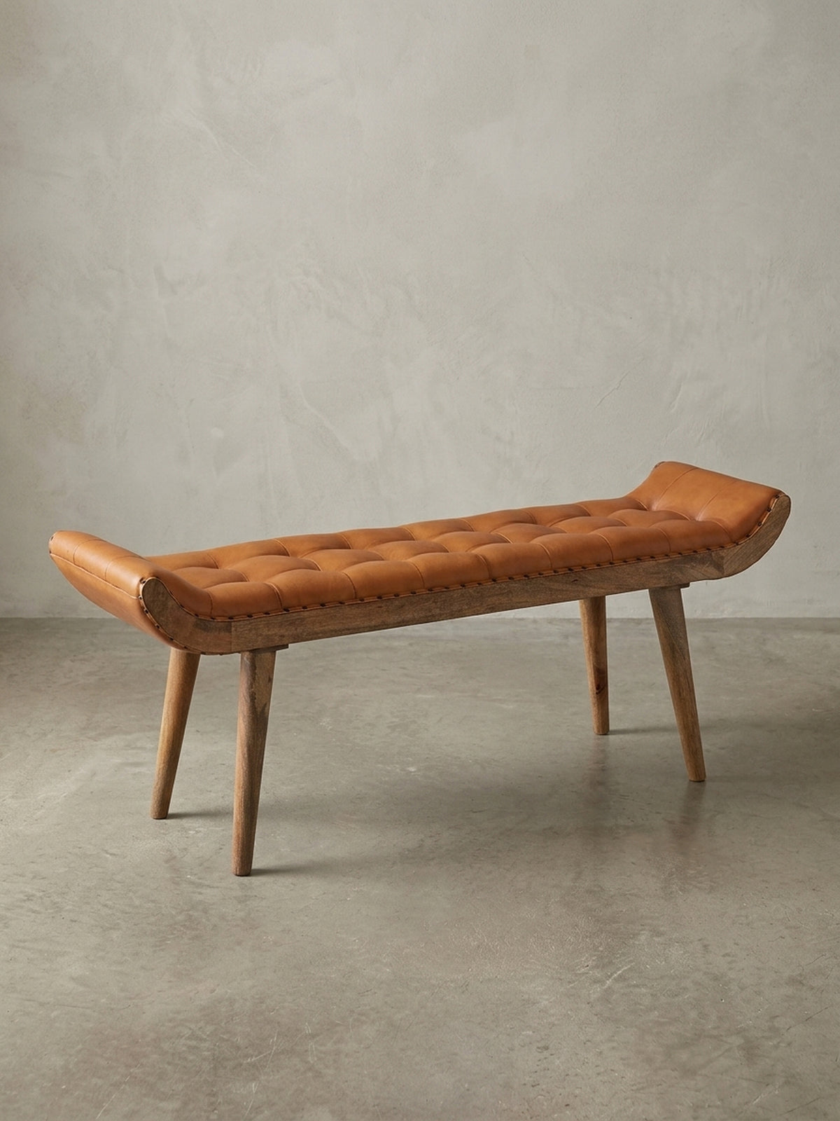 Die Design Sitzbank aus massivem Mangoholz und braunem Echtleder in der Gesamtübersicht. Die getuftete Oberfläche im Chesterfield-Stil ist das zentrale Merkmal.