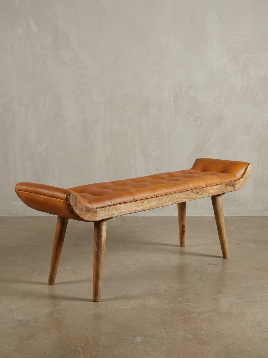 Schräge 3/4-Ansicht der 125 cm langen Polsterbank. Die geschwungene Form und die robusten Beine aus Mangoholz unterstreichen das Vintage-Modern-Design für den Flur._