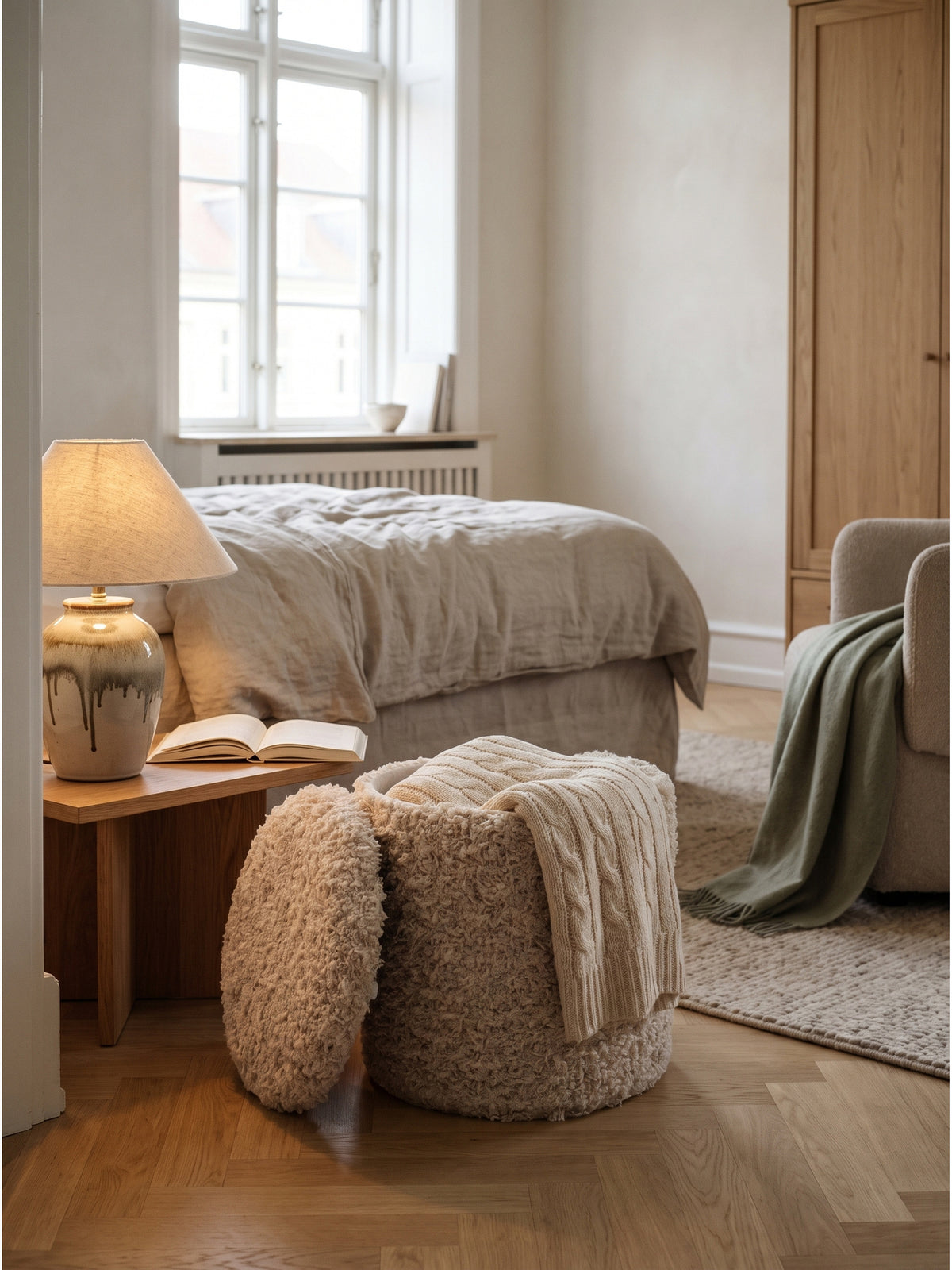 Ein cremefarbener Sitzhocker mit Stauraum arrangiert zusammen mit einem hellen Leinensofa und einem schweren Wollteppich im Schlafzimmer.