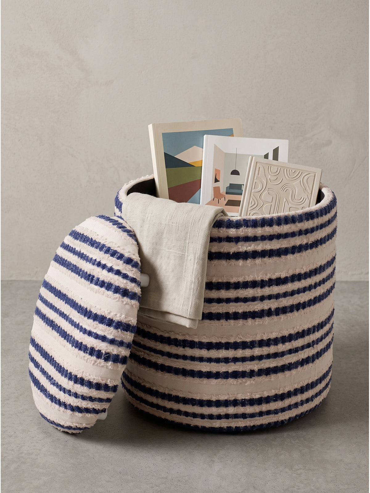 Runder Sitzhocker aus Baumwolle 40x45 cm mit maritimen Streifen in Dunkelblau und Beige isoliert vor neutralem Hintergrund_