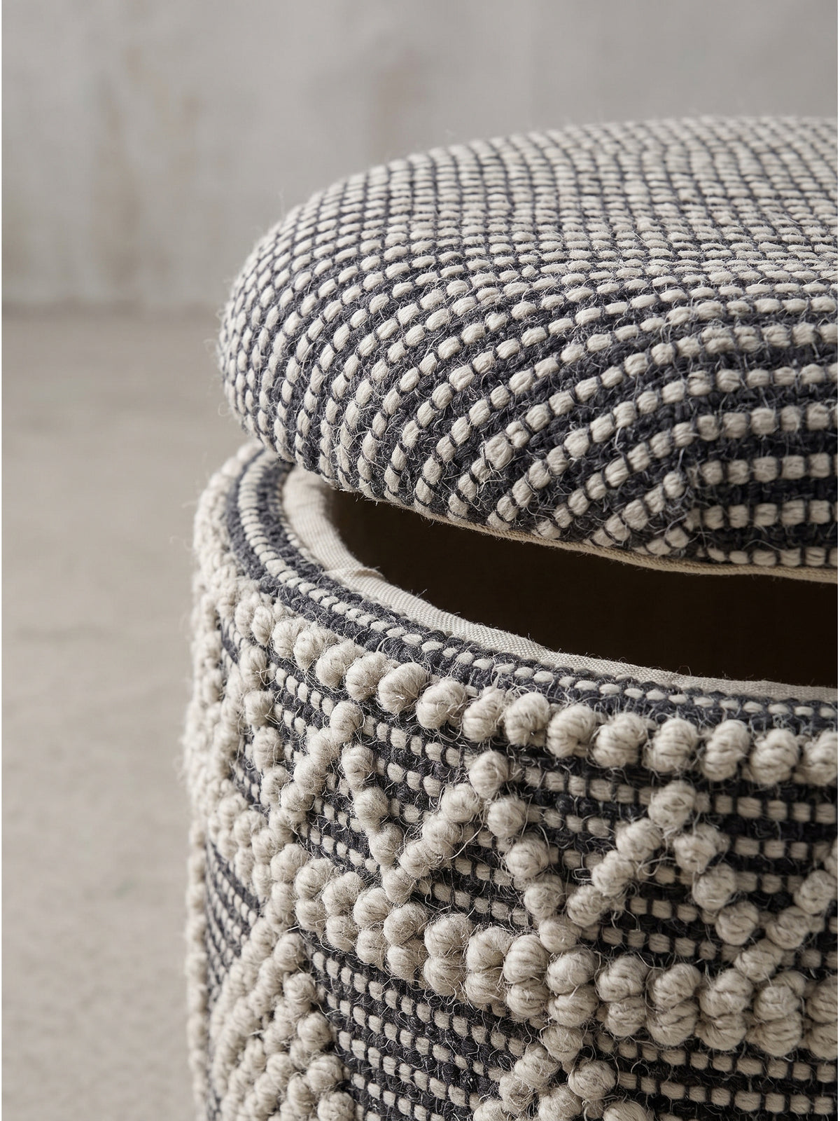 Zylindrischer Pouf aus Wolle in Creme und Grau als vielseitiges Möbelstück für skandinavisch inspirierte Wohnräume