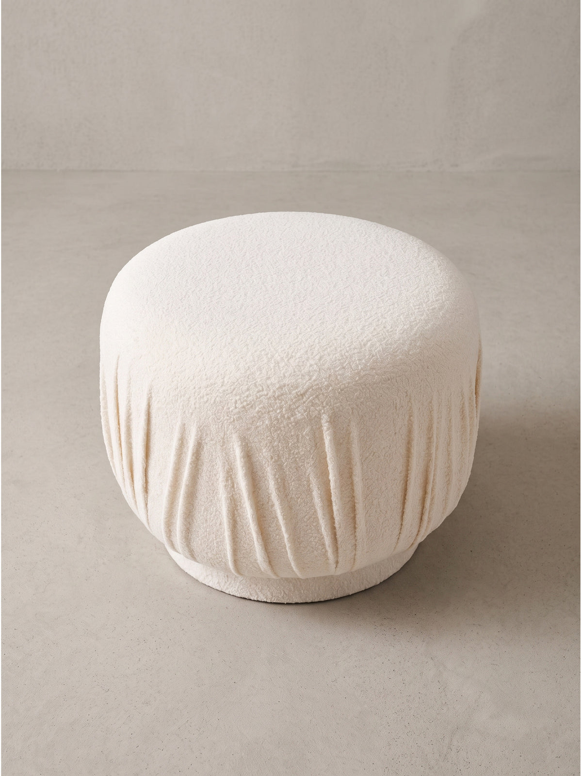 Design Stoffhocker in Creme von schräg vorn mit sichtbarer Struktur des Bezugs und kompaktem Unterbau für gemütlichen Sitzkomfort