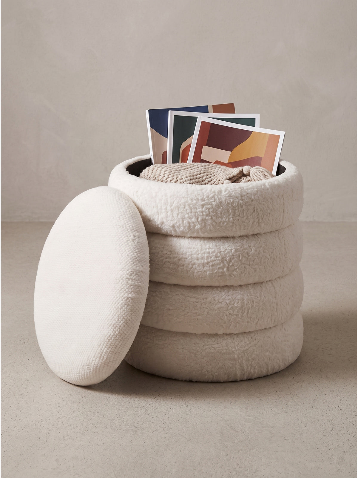 Cremefarbener Sitzhocker mit Stauraum leicht schräg fotografiert zeigt das weiche Polster Design vor weißem Hintergrund_