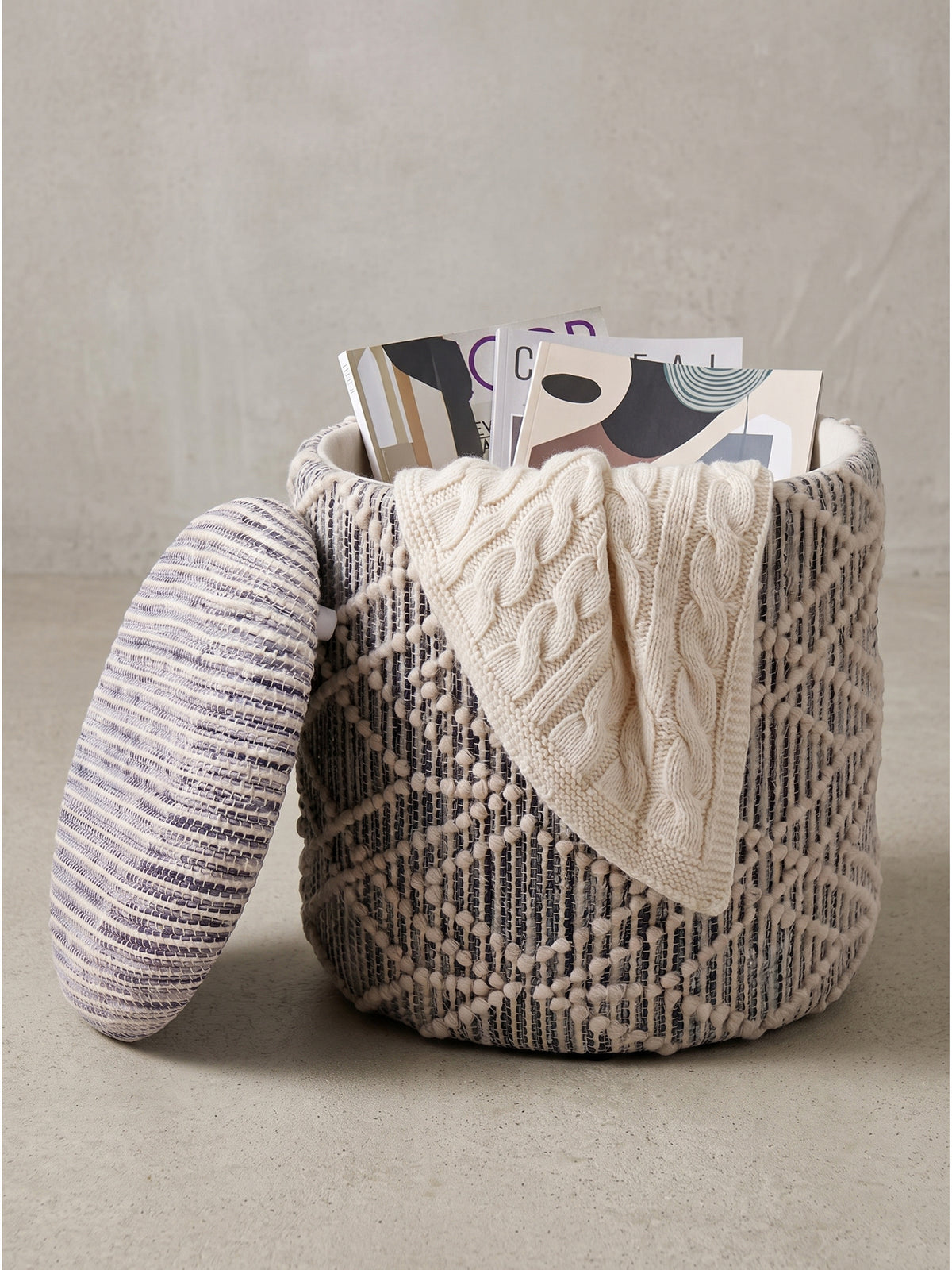 Runder Polsterhocker aus Stoff in Grau und Creme 40x40x45 cm mit offenem Deckel und Zeitschriften_