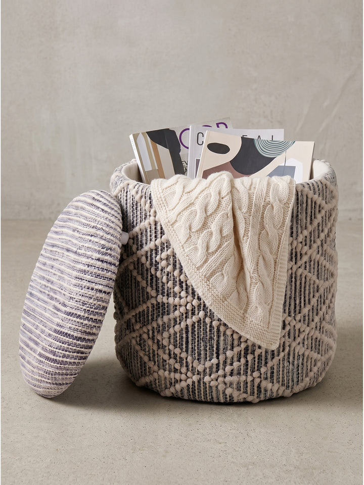 Runder Polsterhocker aus Stoff in Grau und Creme 40x40x45 cm mit offenem Deckel und Zeitschriften_