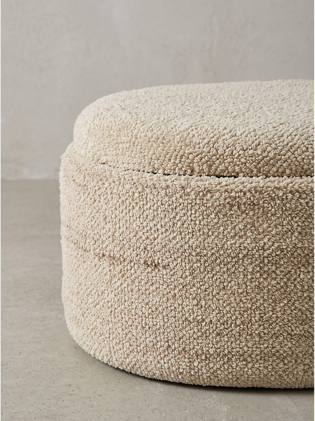 Eleganter ovaler Sitzhocker im organisch modernen Design mit weicher Bouclé-Hülle_
