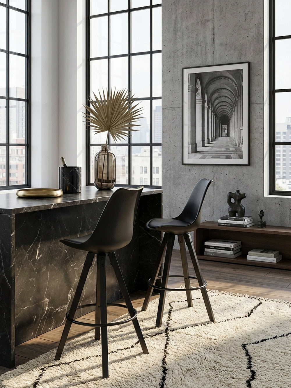 Draufsicht auf ein Set aus zwei schwarzen Design-Barstühlen an einem langen Küchentresen, die das minimalistische Layout und die klaren Linien des Raumes betonen._