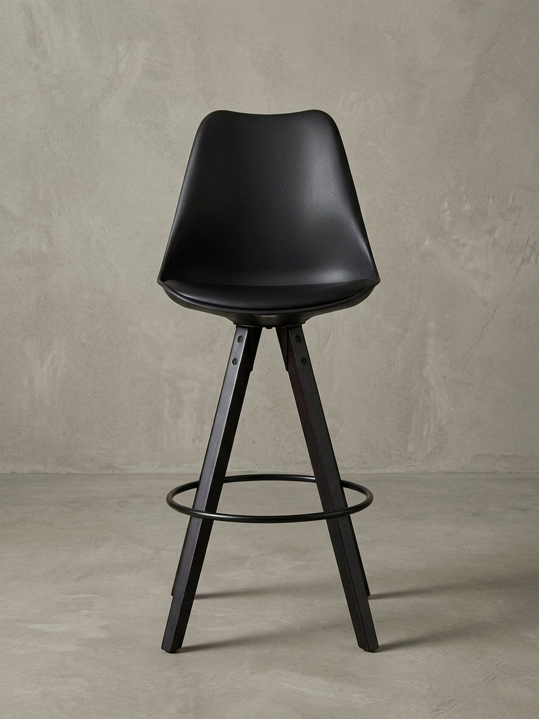 Seitenprofil eines schwarzen Tresenhockers mit hoher Lehne und elegant gespreizten Holzbeinen, ideal für Küchentheken mit 77 cm Sitzhöhe._