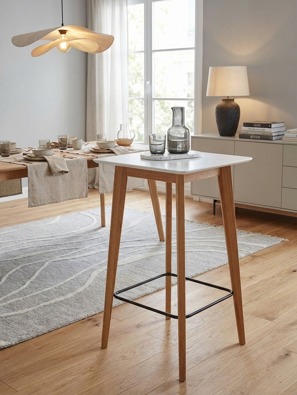 Skandinavischer Stehtisch aus Eiche und Weiß in einem hellen Essbereich, elegant gestylt mit zwei passenden Barhockern auf einem Design-Teppich._