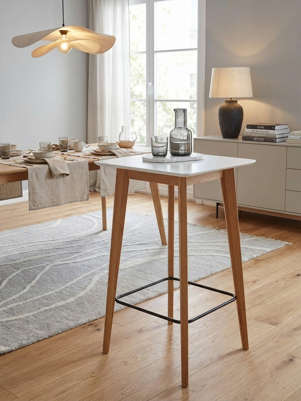 Skandinavischer Stehtisch aus Eiche und Weiß in einem hellen Essbereich, elegant gestylt mit zwei passenden Barhockern auf einem Design-Teppich.