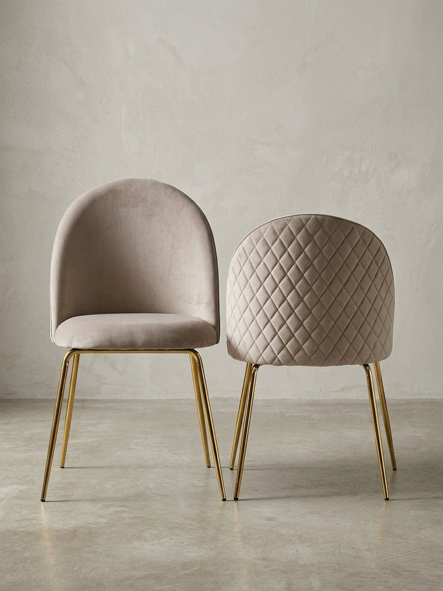 Moderner Esszimmerstuhl aus beigem Samt mit schlanken goldenen Beinen, Frontalansicht auf weißem Hintergrund, Maße B:50cm H:86cm._