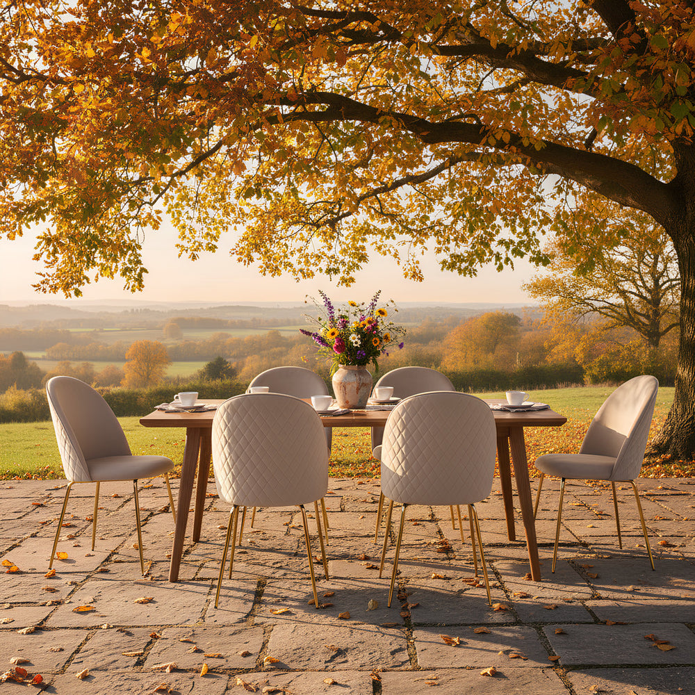 Herbstliche Outdoor-Szene mit Esstisch und Stühlen von Kadima Design. Goldene Blätter am Baum, gedeckter Tisch mit Blumenstrauß und warme Abendstimmung_