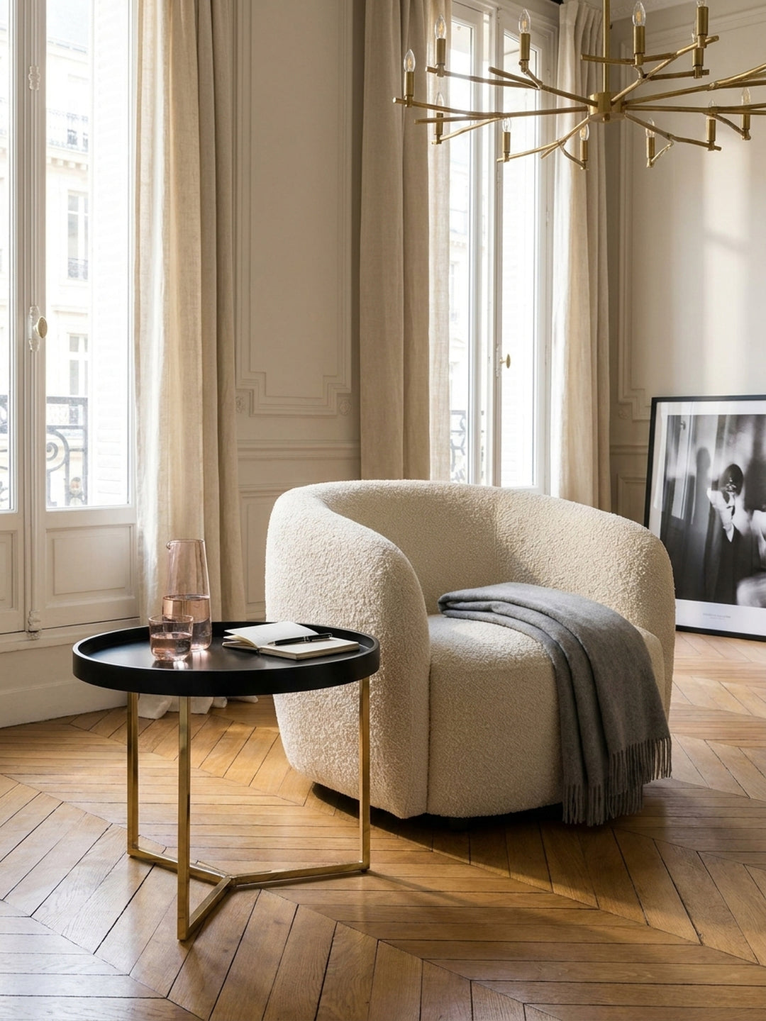 Eleganter Loungetisch schwarz-gold harmonisch arrangiert mit einer skulpturalen Messing-Stehlampe und abstrakter Kunst im lichtdurchfluteten Wohnbereich._