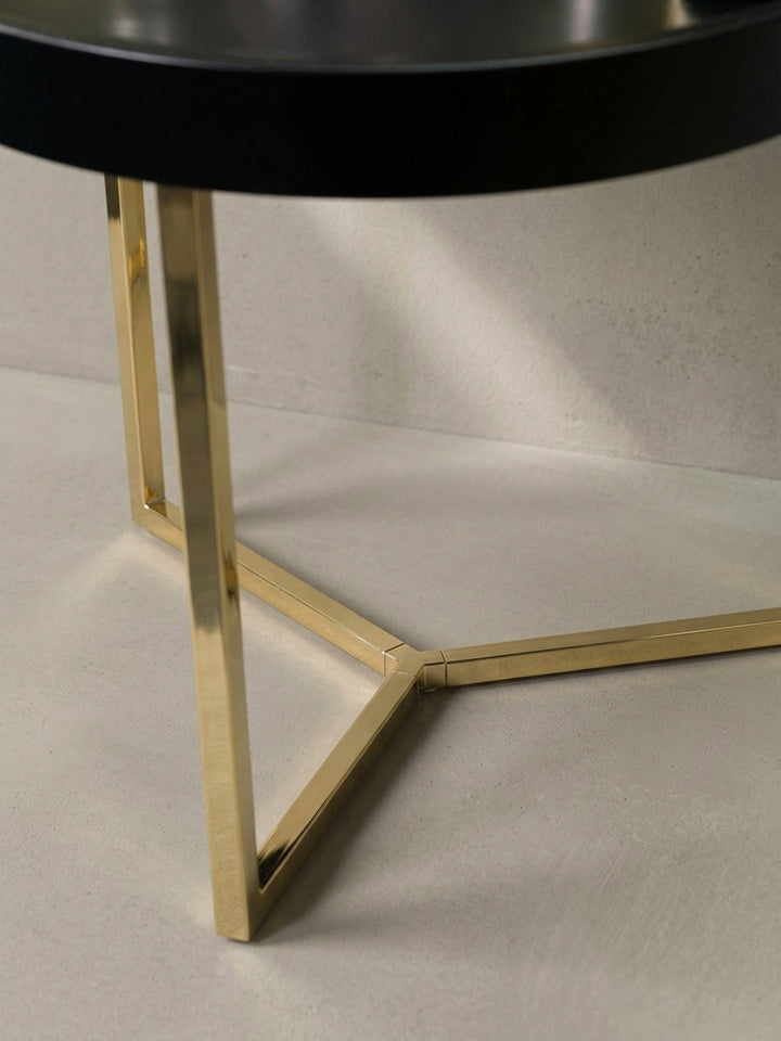 Detailaufnahme der feinen Verbindungen am goldfarbenen Stahlgestell und der holzschonenden Kunststoff-Noppen an der runden Tischunterseite._