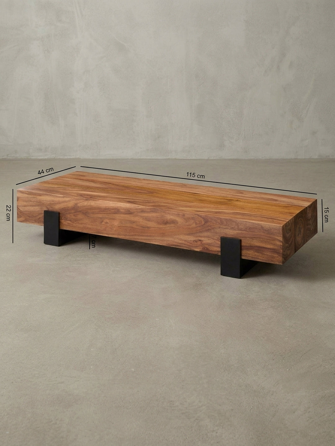 Detailansicht der Rückseite des rechteckigen Stubentisches. Stabile Konstruktion des 115x44cm Holzblocks mit nahtlosem Übergang zu den bodennahen schwarzen Metallstützen des Gestells._