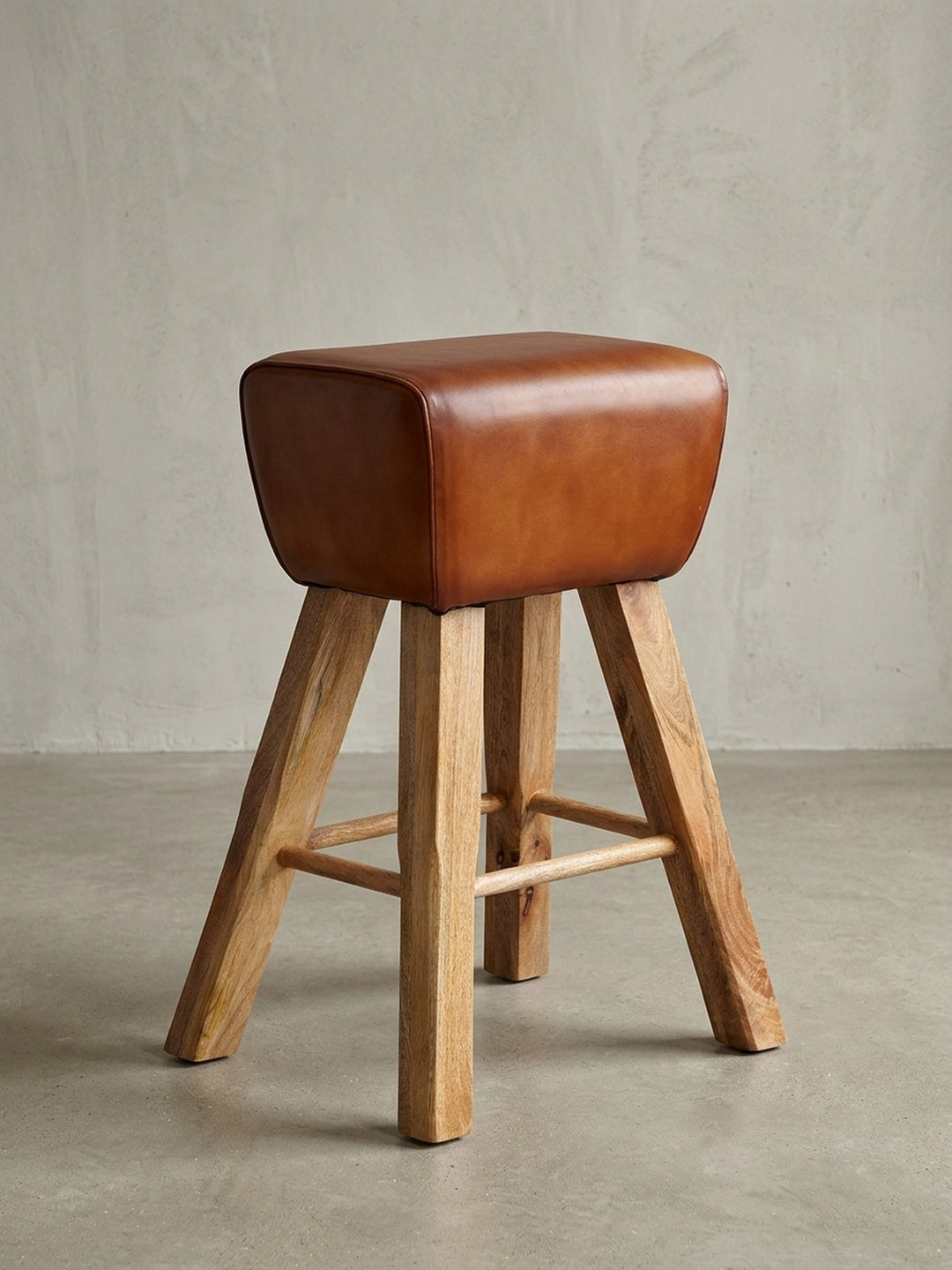 Studioaufnahme des Barhockers im Turnbock-Design mit braunem Echtleder-Sitz und massivem Mangoholz-Gestell, Frontalansicht auf weißem Hintergrund._