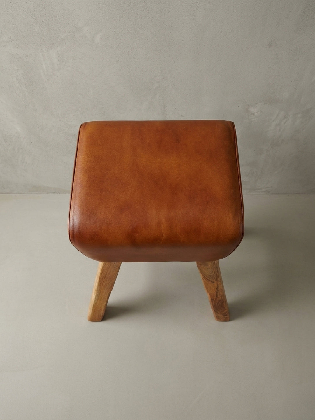 Einzigartiger Barstuhl im Turnbock-Stil, fotografiert aus einer alternativen Perspektive, die das Zusammenspiel von Leder und Mangoholz betont._