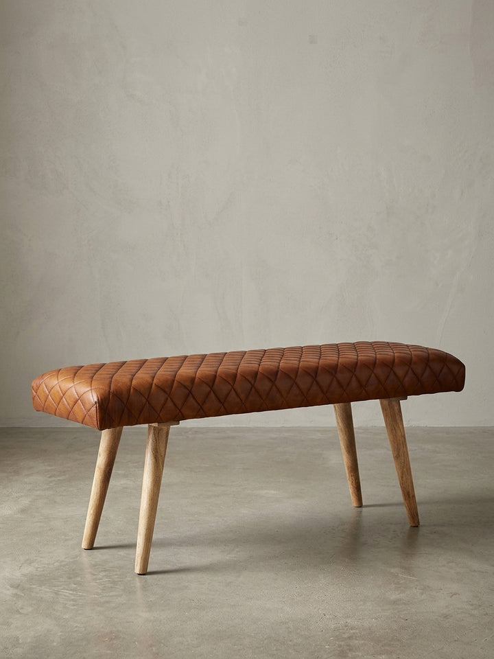 Freigestellte Frontansicht der Sitzbank aus Echtleder in Braun mit Beinen aus massivem Mangoholz. Die klassische Rautensteppung verleiht der Bank ihren Charakter._
