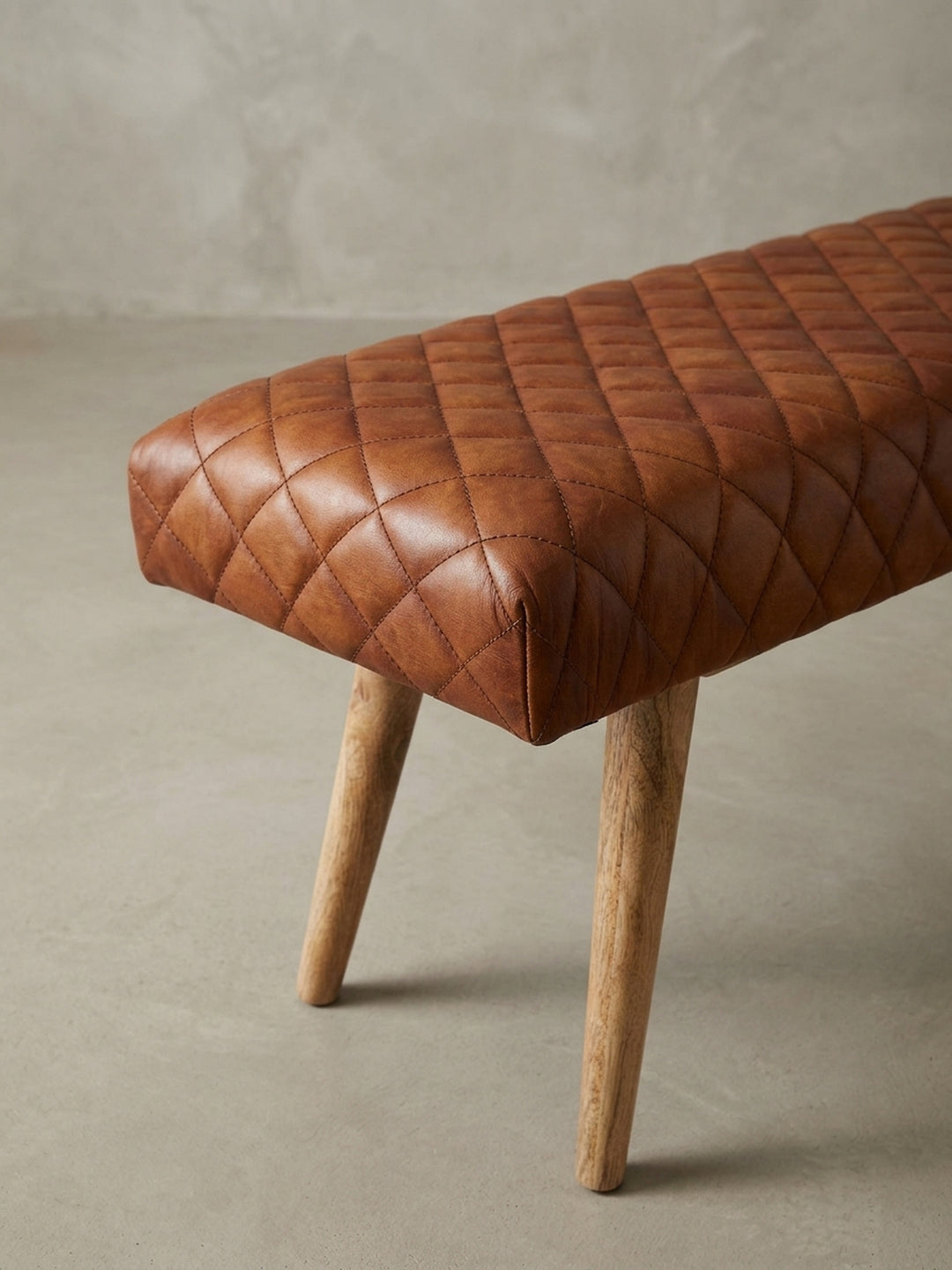 Nahaufnahme eines der konisch zulaufenden Beine aus massivem Mangoholz, das die feine Maserung des Holzes und die solide Befestigung an der Sitzfläche zeigt._