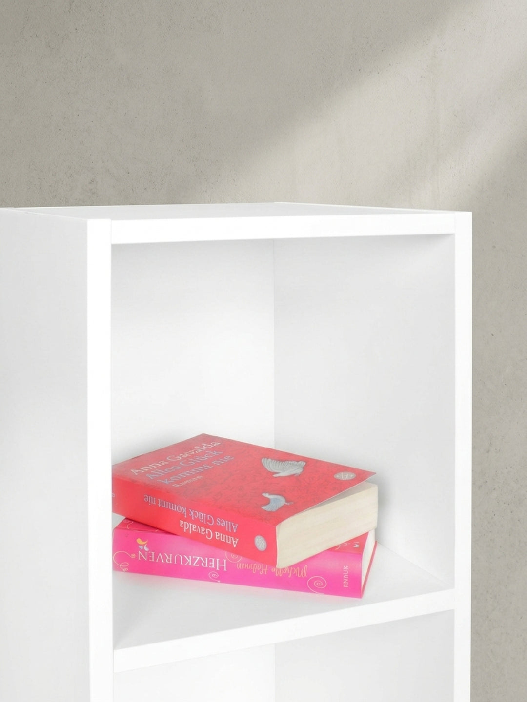 Nahaufnahme der inneren Regalbretter im weißen Standregal, perfekt bemessen für Taschenbücher, DVDs oder kleine Deko-Objekte._