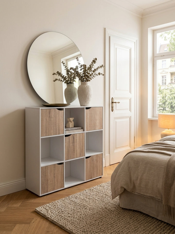 Draufsicht auf das kompakte Würfelregal im Wohnzimmer. Das 29 cm tiefe Bücherregal fügt sich platzsparend an die warmweiße Wand, dekoriert mit einer Keramikvase und Bildbänden._