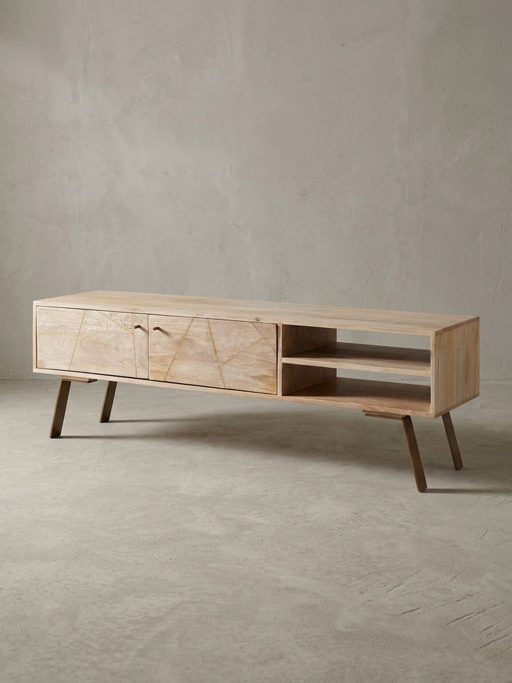 Vorderansicht des 145cm breiten TV-Unterschranks aus Mangoholz. Zwei Türen mit geometrischem Muster und offene Ablagefächer auf dunklen Eisenbeinen im klaren Studio-Licht._
