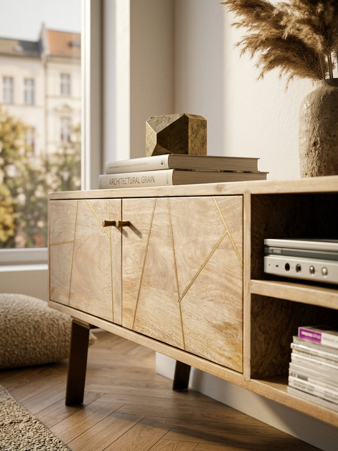 Nahaufnahme der edlen Holzmaserung des Sikar Lowboards. Die geometrischen Metallstreifen in Messingoptik auf dem massiven Mangoholz unterstreichen das hochwertige Möbel-Design._
