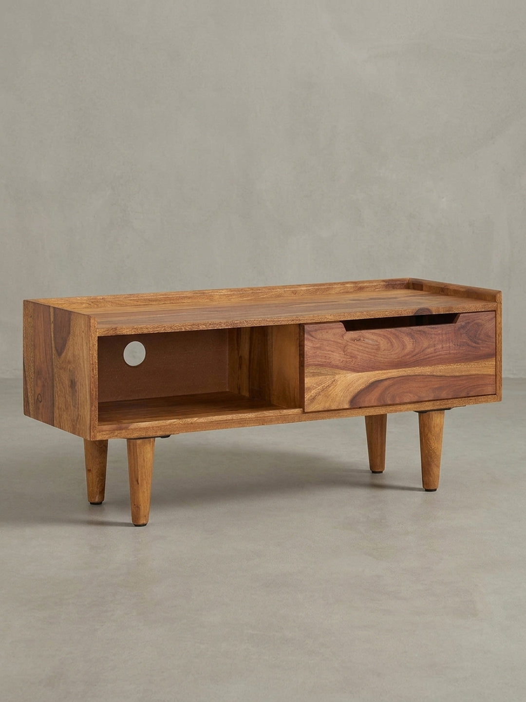 Design TV-Schrank 95x44x34 cm aus Sheesham in einer 3/4-Ansicht, die das offene Staufach mit Kabeldurchlass und die Schiebetür zeigt._