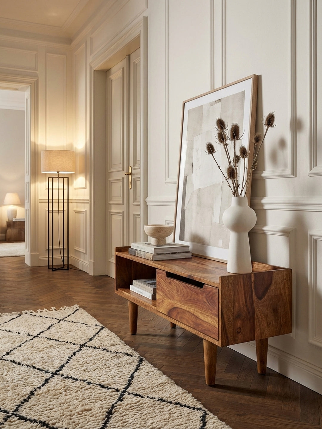Modernes Lowboard aus massivem Sheesham-Holz im Wohnzimmer, stilvoll dekoriert mit Büchern und einer Vase unter einem Fernseher an einer grauen Wand._