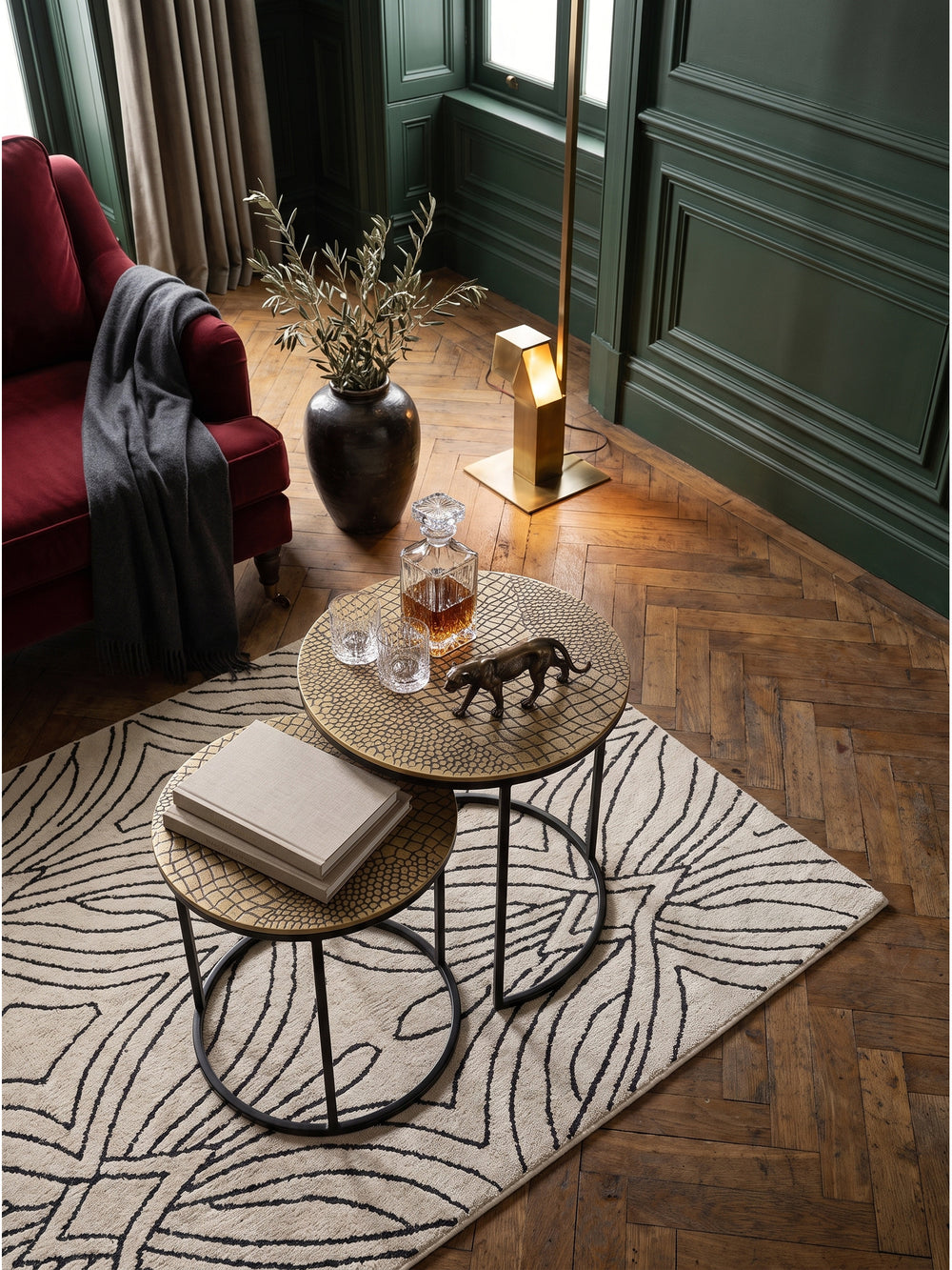 Blick von schräg oben auf den zweiteiligen Couchtisch mit goldener Krokodilprägung, flexibel arrangiert auf einem geometrischen Art-Deco-Teppich im stilvollen Pariser Apartment_