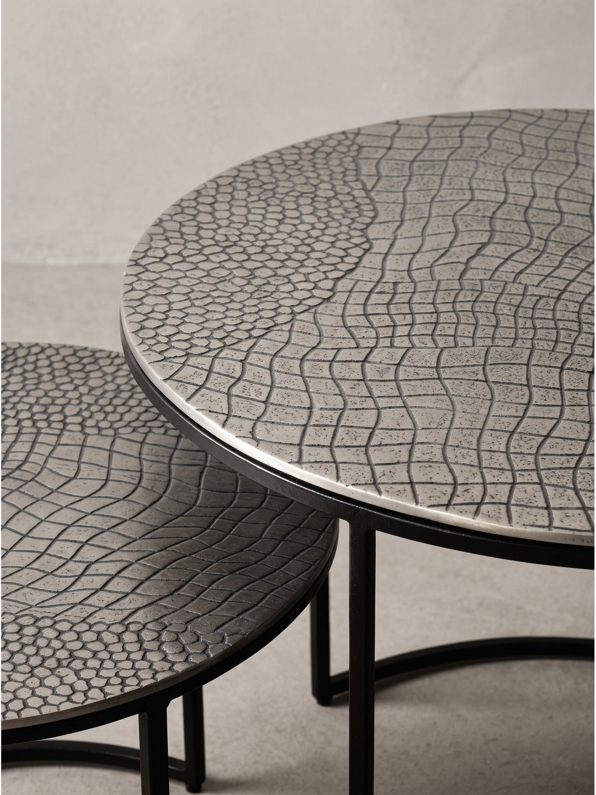 Der leicht versetzte kleine Sofatisch aus strukturiertem Aluminium erweitert den größeren Haupttisch zu einer flexiblen Ablagefläche.