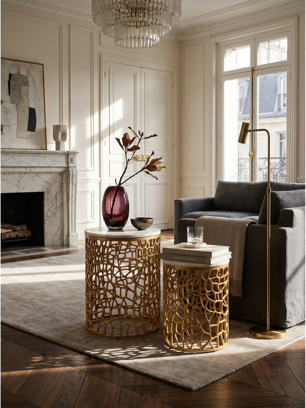Elegantes Satztisch Set aus Echtmarmor und goldenem Aluminium im klassischen Pariser Wohnzimmer auf dunklem Fischgrätparkett_