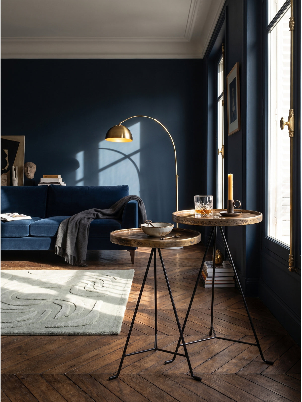 Zwei goldene Satztische aus Aluminium und schwarzem Eisen im eleganten Vintage-Wohnzimmer vor einer mitternachtsblauen Wand.