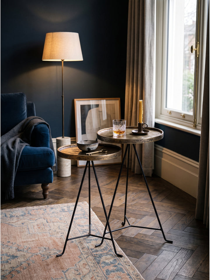 Ein raffiniertes Wohnzimmer-Ensemble aus den schwarzen Satztischen und einem blauen Loungesofa in klassischer Altbauumgebung._