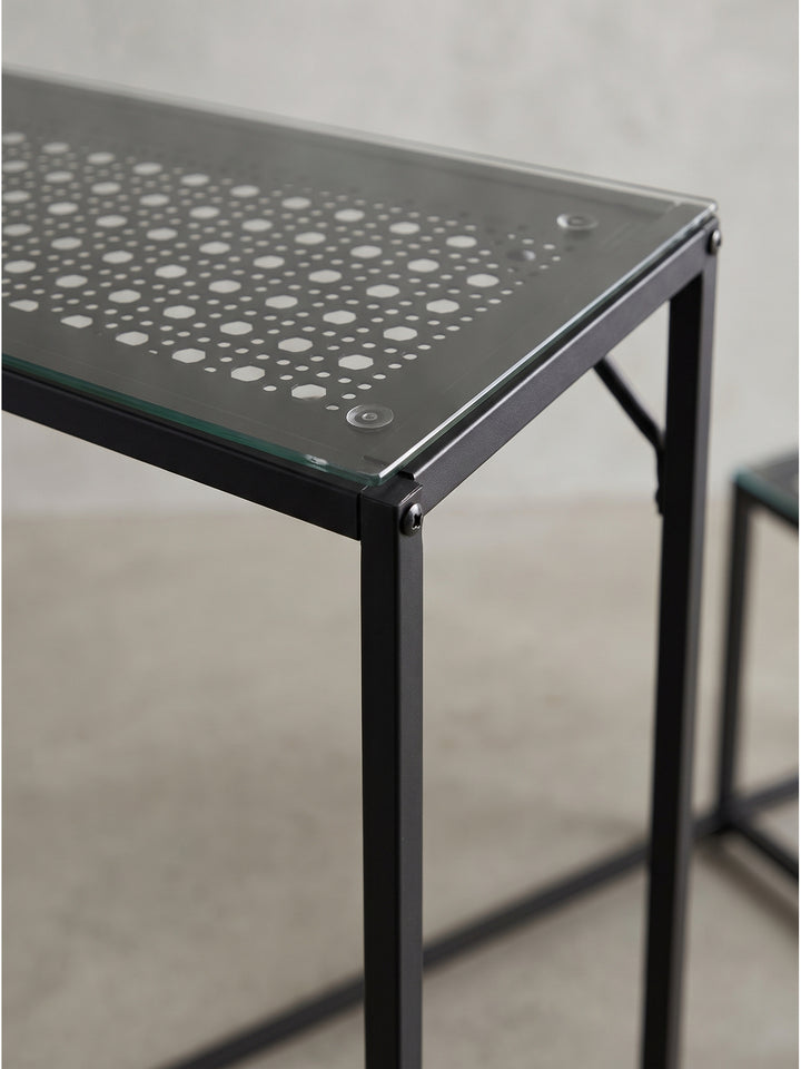 Detaillierte Perspektive auf das schwarze Konsolentisch Set mit Fokus auf das durchbrochene Metallgitter unter dem Glas_