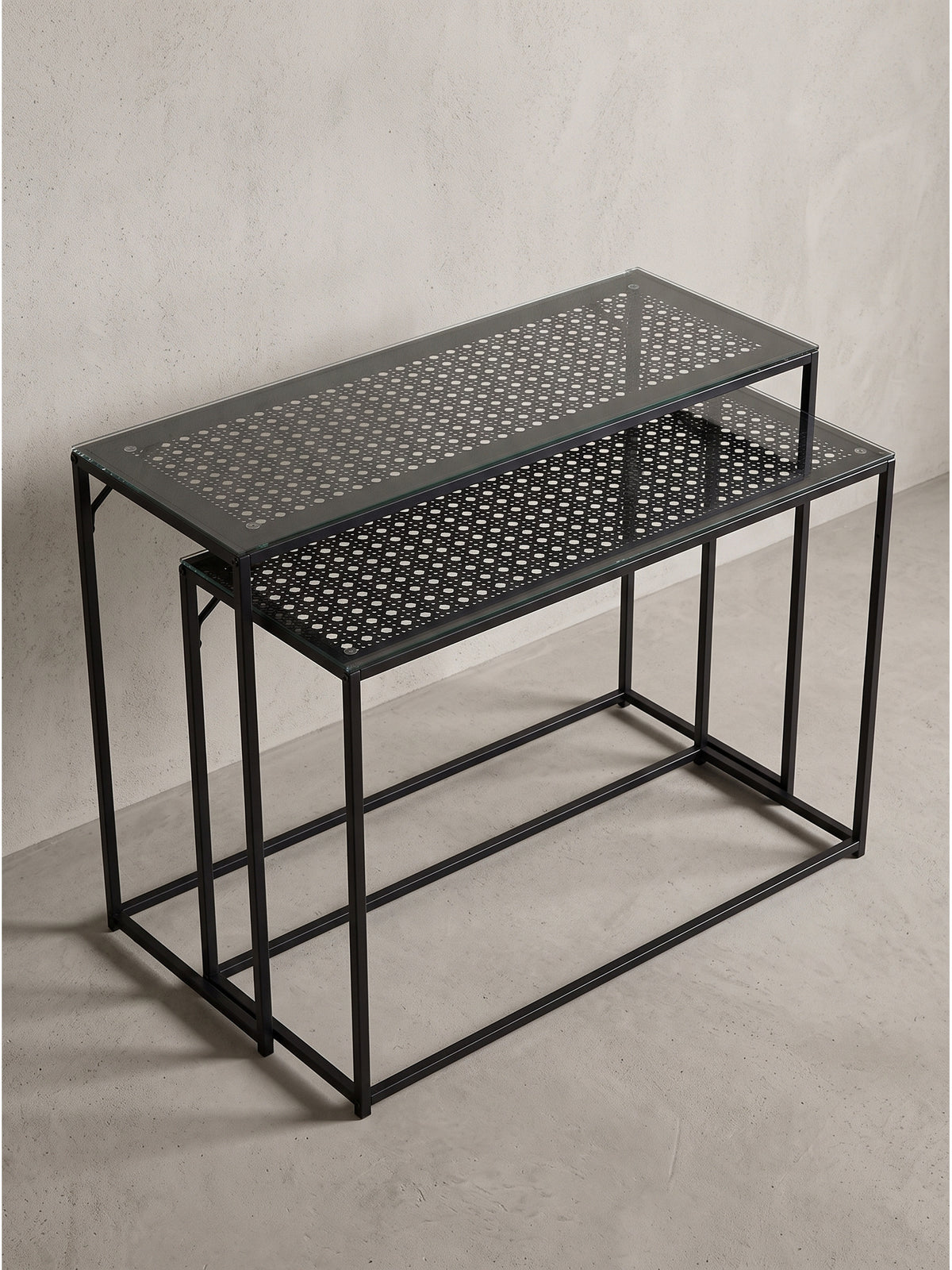 Seitenansicht des platzsparenden schwarzen Konsolentisch Sets mit versetzten Ebenen aus Glas und perforiertem Metall_